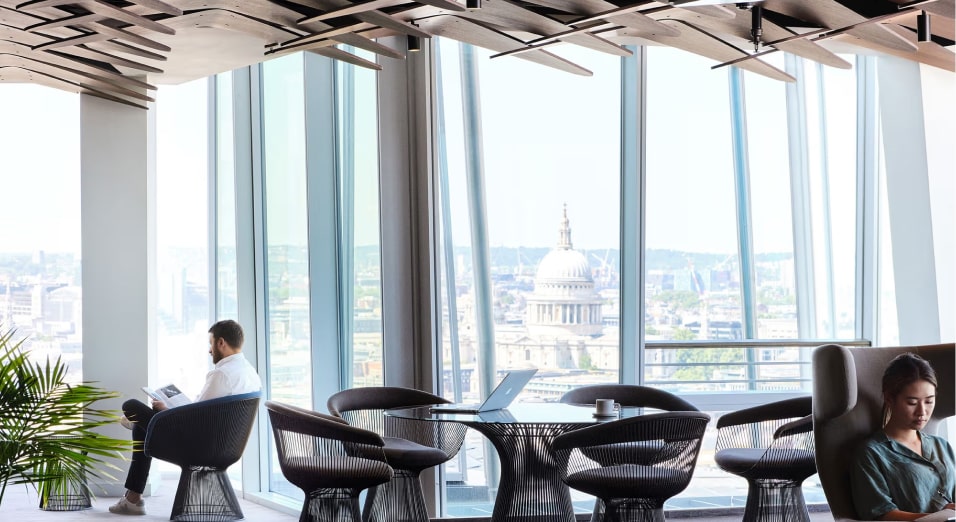 Modern office lounge with city view through large windows.