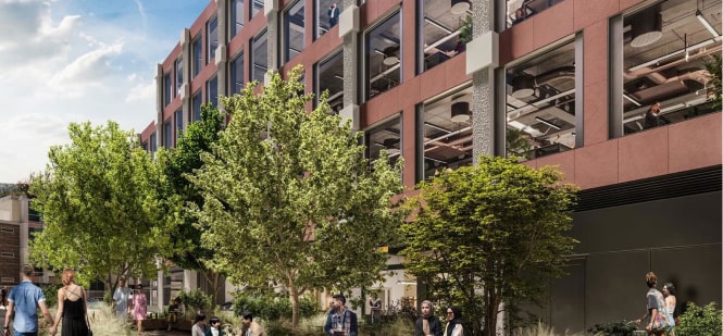 Modern office building with outdoor greenery and people walking nearby.